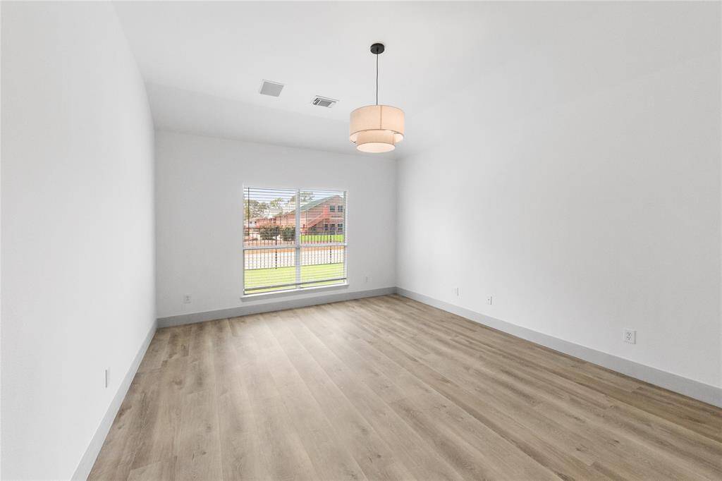 Large primary bedroom with natural light and center chandelier