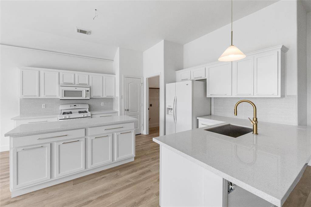 Large and light kitchen with gold accents and stone countertops
