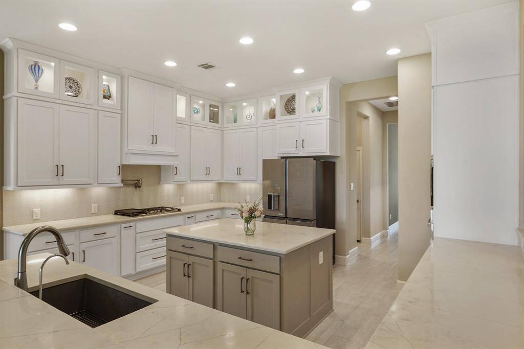 Alternate kitchen view highlighting the oversized island, 5 burner GE Monogram gas stove with pot filler, access to the butler’s pantry, and large under mount sink with a built-in filtration system.