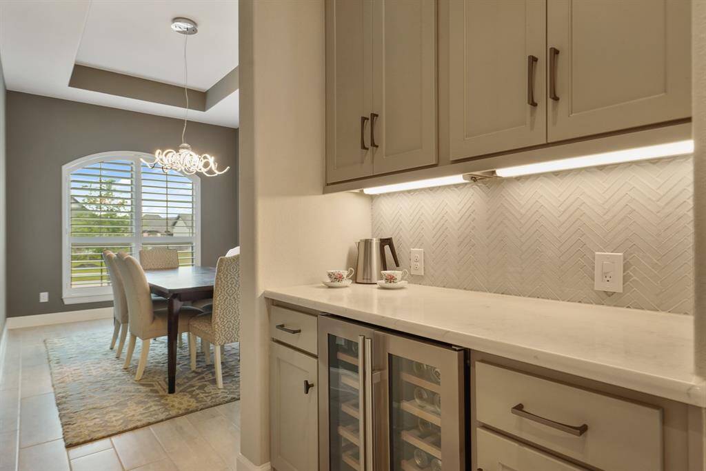 The butler's pantry featuring beautiful cabinets, a 2 door beverage fridge, and under-cabinet lighting is conveniently located next to the formal dining, for effortless entertaining.