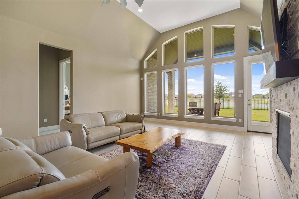 Another view of the expansive living area showcases floor-to-ceiling windows that frame the covered patio and offer serene views of the lake.