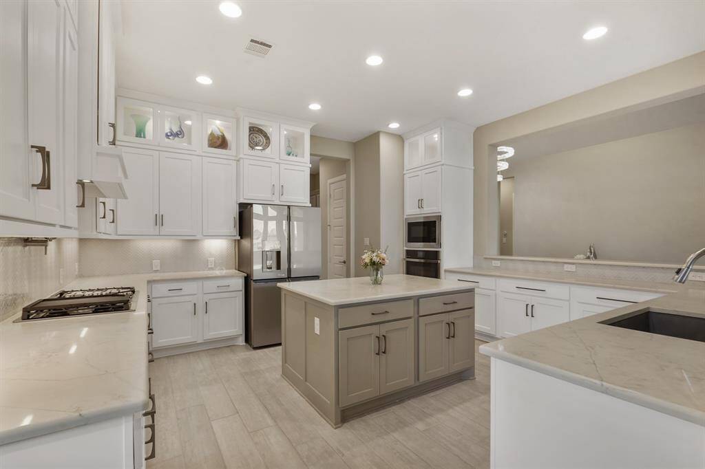 The kitchen highlights quartz counters, extended kitchen cabinets, water filtration system, pot filler, a contrasting island, a butler pantry, and sleek stainless-steel GE Monogram appliances.