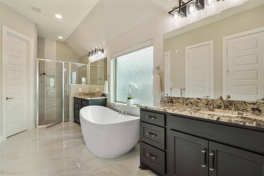 The spa-like primary bathroom features a freestanding tub, oversized glass enclosed shower, linen closet, dual vanities, and two walk-n closets.