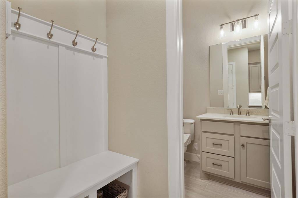 Upon entering from the garage, there is a mudroom with built-in bench seating, and a powder bathroom for everyday convenience.