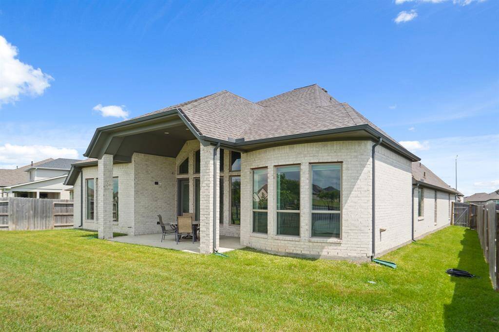 The rear elevation reveals the spacious covered patio, large picture windows, and elegant rooflines.