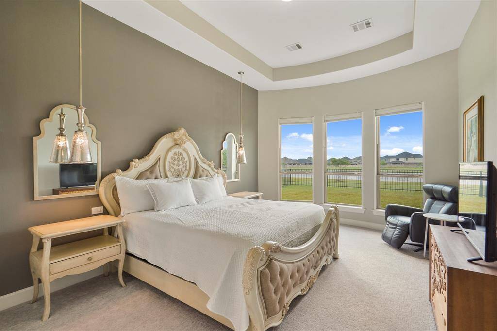 The spacious primary bedroom features a tiered ceiling and large bay windows overlooking the lake, offering the ultimate retreat to unwind after a long day.