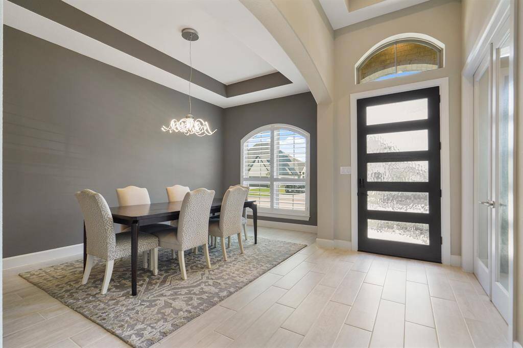 Upon entry, a soaring ceiling, and glass paneled front door, frame the formal dining room to the right, creating a bright and welcoming foyer.