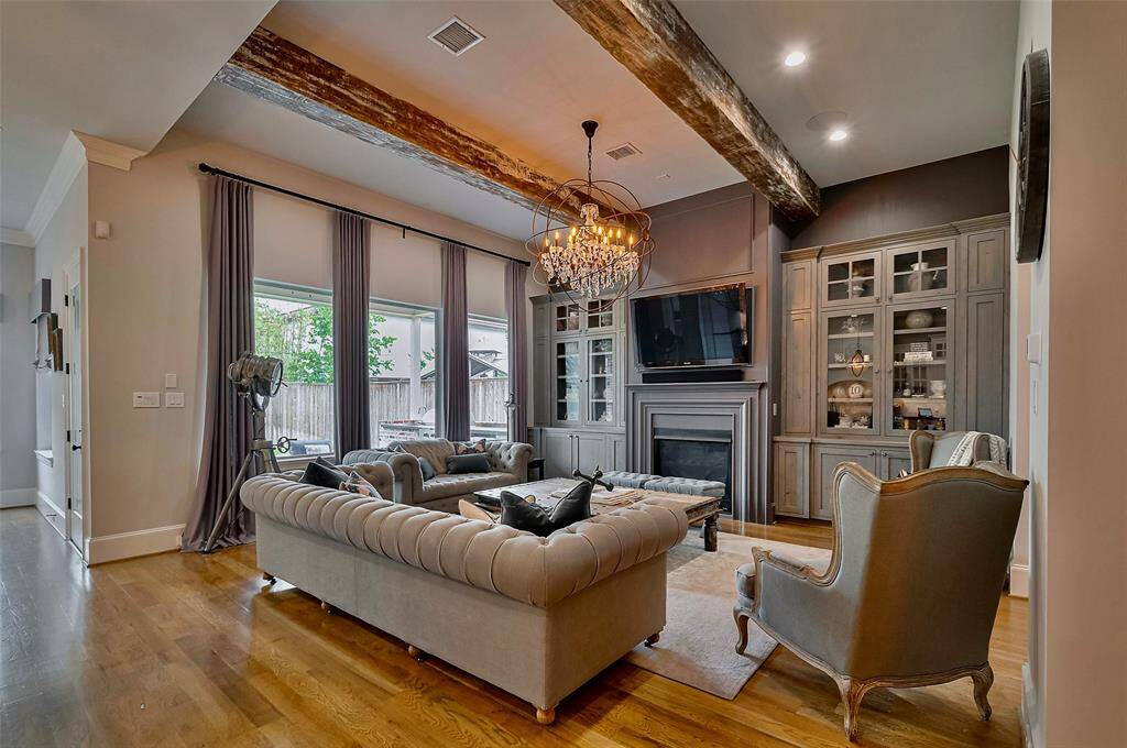 With 12-foot ceilings and exposed distressed wood beams, this elegant living space exudes warmth and character. A 42” gas-burning fireplace is flanked by custom built-ins, while a Restoration Hardware chandelier and tailored window treatments add a refined, designer touch. Perfectly balanced between cozy and sophisticated.