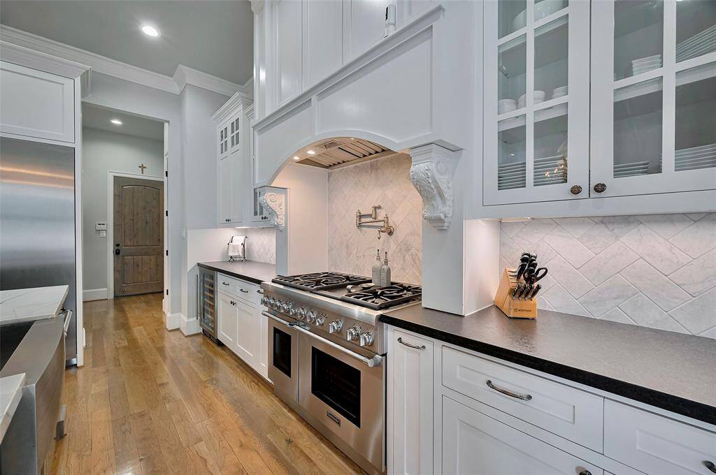Kitchen features a stunning herringbone tile backsplash that adds texture and visual interest. The countertops, finished in sleek Homed Black Pearl granite, provide a durable and stylish workspace.