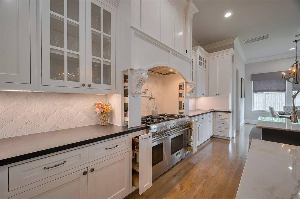Clever design details shine with corbels featuring hidden utensil holders and spice racks, offering style and convenience in one. An appliance garage keeps countertops sleek and clutter-free. Effortless beauty meets everyday function in this thoughtfully crafted kitchen.