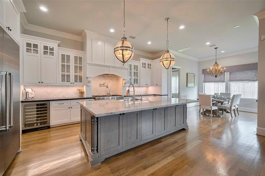 Luxury meets function with designer light fixtures, a Thermador built-in fridge, wine refrigerator, and storage on both sides of island. Enjoy instant hot water, dual dishwashers (including one in the utility room), and elegant crown molding throughout.