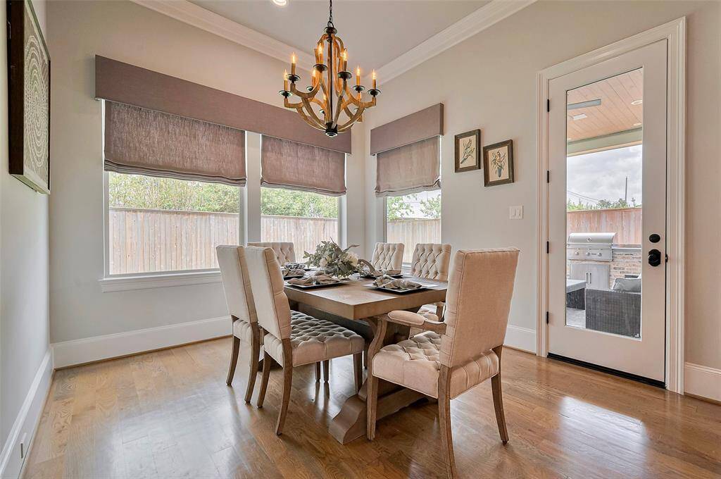 The charming breakfast room offers a serene view of the backyard, filling the space with natural light. Custom Roman shades add a soft, tailored touch—blending comfort and style for relaxed everyday dining