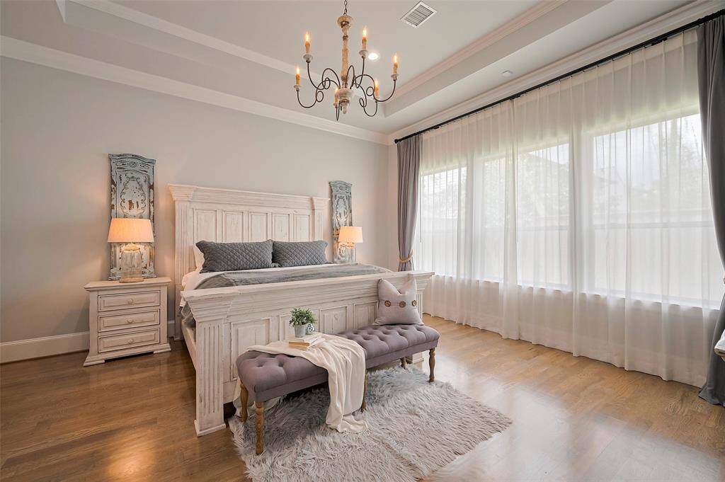 The spacious primary bedroom exudes quiet luxury with 12’ ceilings, a tray ceiling design, and extra-large crown molding. Hardwood floors and recessed lighting add warmth and elegance, while Restoration Hardware custom blackout drapes, sheer curtains, and signature rope tie-backs provide both beauty and functionality for a perfectly polished retreat.