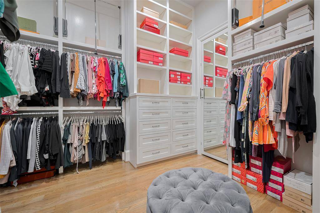 The primary closet is both spacious and impeccably designed, featuring tall ceilings, three-tier hanging rods, and a convenient pull-down bar for easy access. Built-in drawers and shelving offer ample storage and organization, making this a truly functional and luxurious dressing space.
