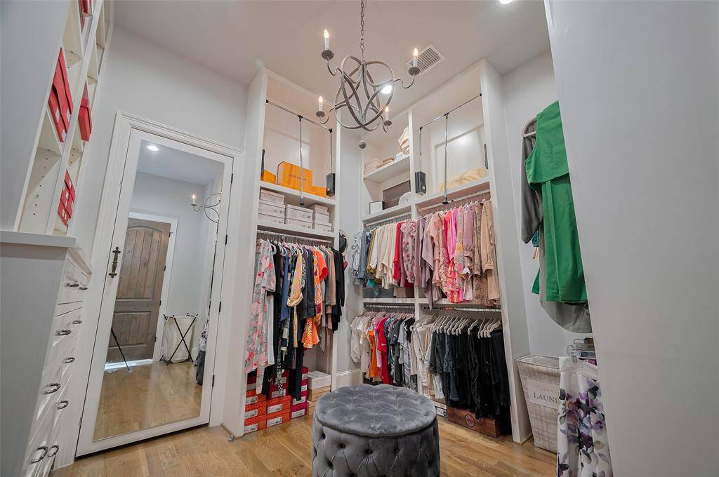A large mirrored door offers both elegance and convenience, providing direct access to the utility room. Topped with a sparkling chandelier, the space feels like a private boutique—thoughtfully designed for effortless organization and everyday luxury. Mirrored door leads to the laundry room for added convenience.
