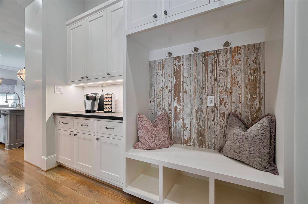 The utility room is both practical and stylish, featuring a custom Roman shade, built-in sink, and space for an additional refrigerator. One of the home’s two dishwashers is conveniently located here, making cleanup and organization effortless. A dedicated wall space offers the perfect spot for hanging, adding to the room’s smart, functional design. Secret door leading to primary closet.