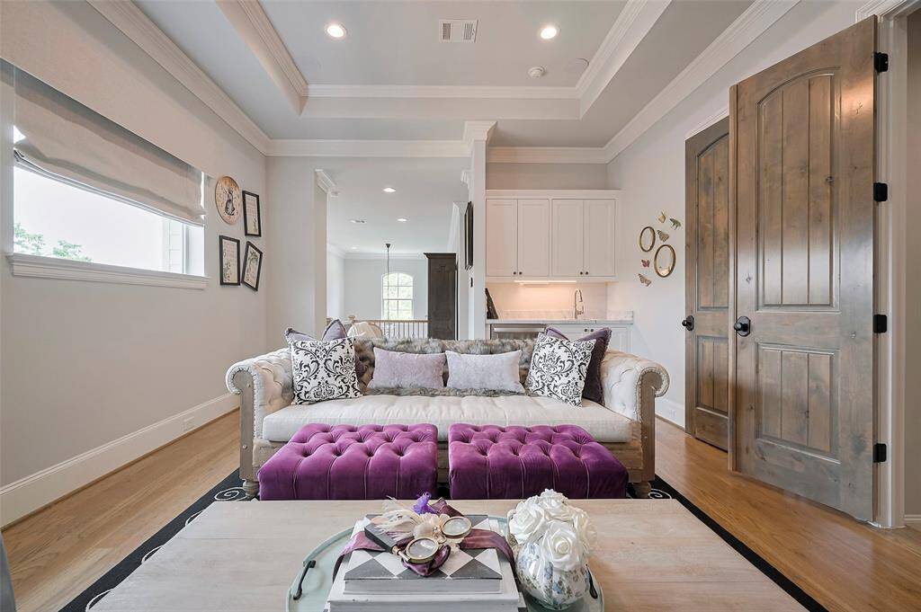 The game room is both stylish and functional, featuring recessed lighting, hardwood floors, and a designer ceiling fan with remote for year-round comfort. A custom wet bar with built-in cabinets, under-cabinet lighting, and a beverage refrigerator makes entertaining a breeze. A large closet includes a built-in desk, drawers, cabinets, and shelving—perfect for crafts, hobbies, or extra storage. This space is designed to flex with your lifestyle.