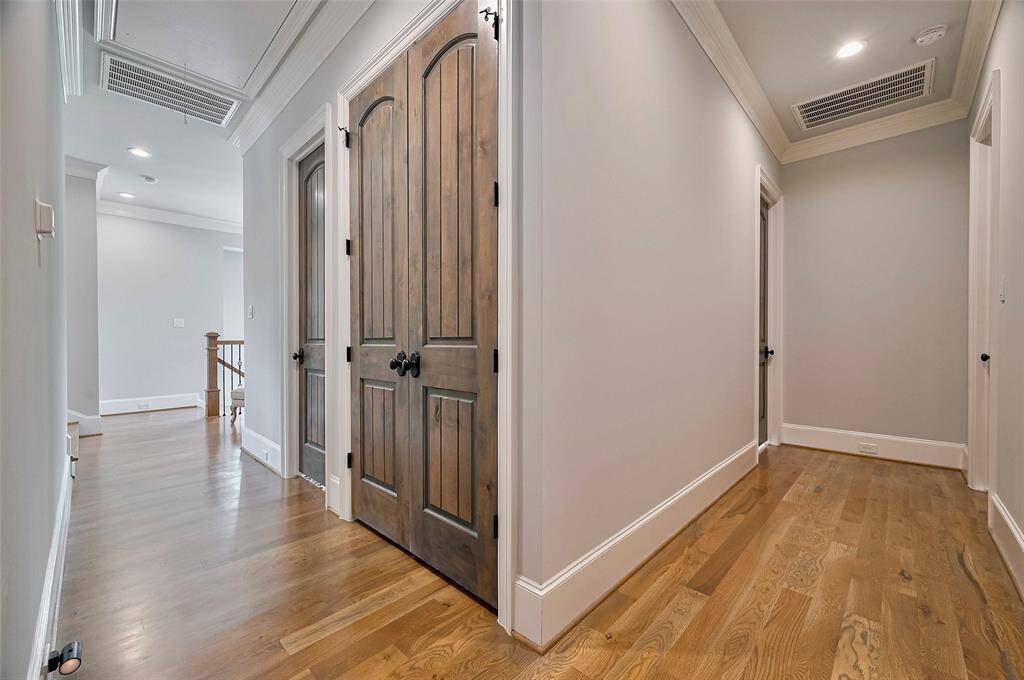 A wide hallway with rich hardwood floors creates a warm and inviting transition to the home’s three secondary bedrooms. A large storage closet adds practical convenience, making this space as functional as it is beautiful. Additional closet storage at the end of the hallway at the top of the stairs.