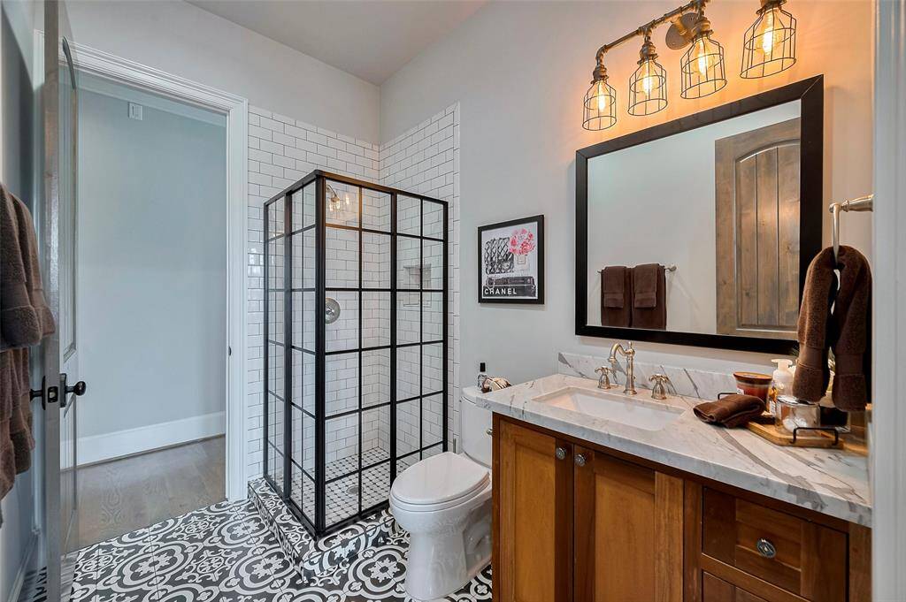 The en suite bathroom showcases designer tile, a charming vintage-style light fixture, and premium finishes throughout. All bathrooms feature Toto toilets with elongated seats, combining classic elegance with modern comfort.