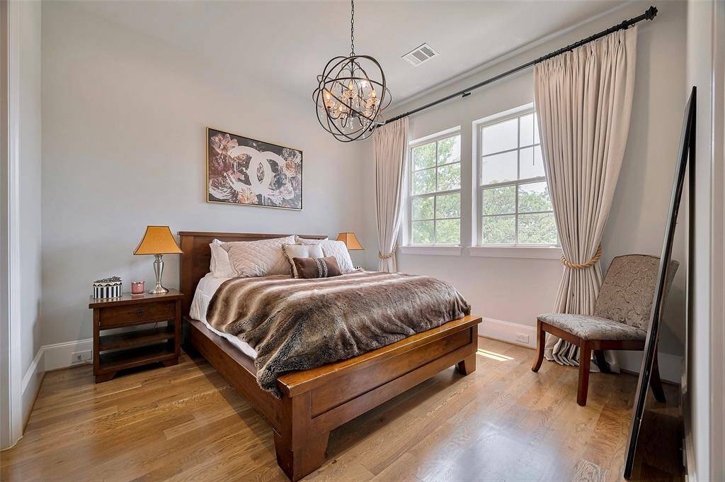 This spacious guest room offers comfort and style with a walk-in closet, a striking orb chandelier, and a beautiful view of the front of the home. A perfect blend of elegance and warmth for overnight guests.