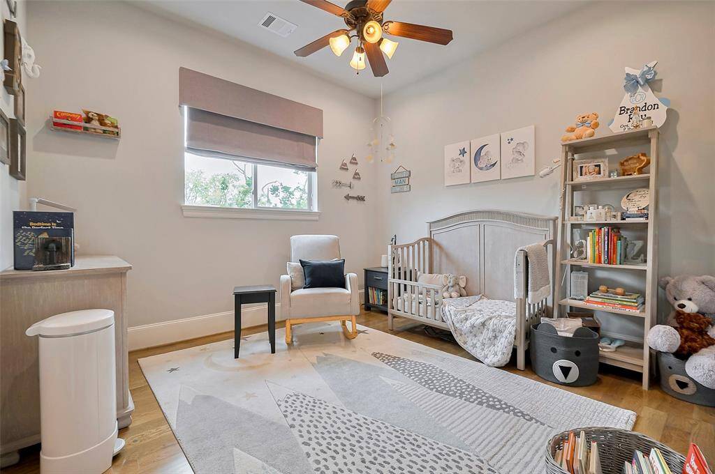 Another inviting secondary bedroom features elegant custom Roman shades and a walk-in closet with built-in shelving, blending timeless style with smart, functional storage.
