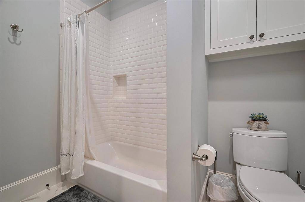 The Jack and Jill bathroom features classic beveled subway tile and smart storage solutions, including a cabinet above the toilet. Each connected bedroom enjoys its own sink with custom cabinetry, blending function with timeless design.