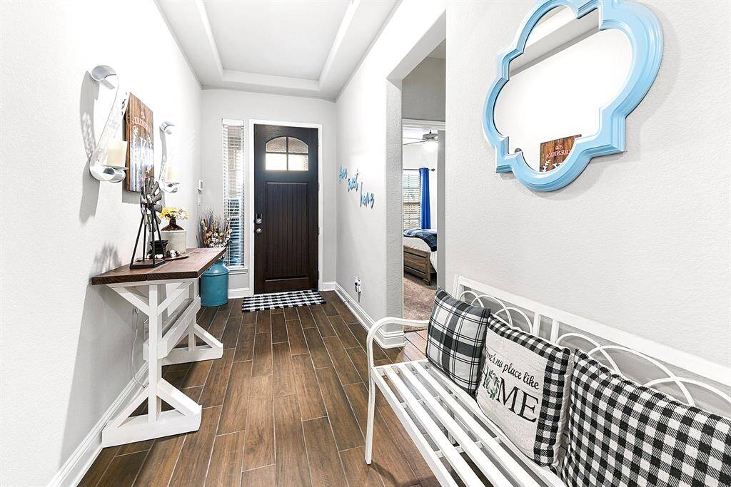 Inviting entryway with lovely wood look tile and tray ceilings.