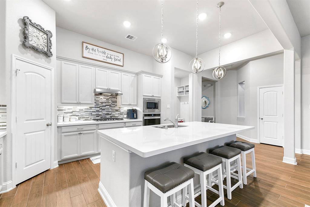 Exquisite kitchen! White granite countertops, 42 inch white cabinets with added hardware, trendy mosaic tile backsplash and upgraded pendant lighting.