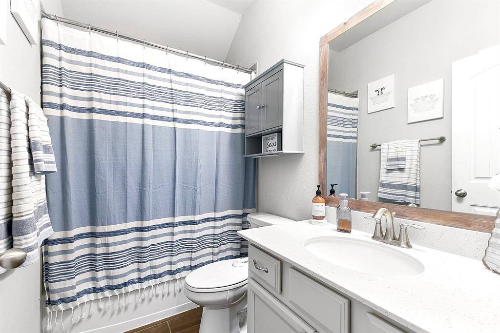 Secondary bath is located between the two bedrooms.  Also with white cabinets, added hardware, shower/bath combo and cabinetry added above the toilet.