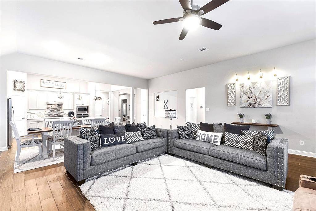 Agreeable gray walls and large wood look tile plank flooring throughout main rooms. The floorplan boasts a vast, open-concept family room and dining space, offering an expansive and inviting area perfect for gatherings and entertainment.