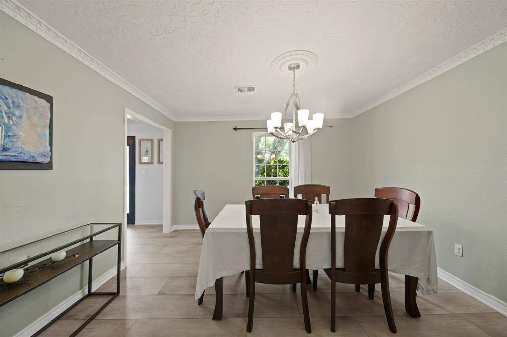 This dining room has natural light, tile floors, custom paint, and crown molding.