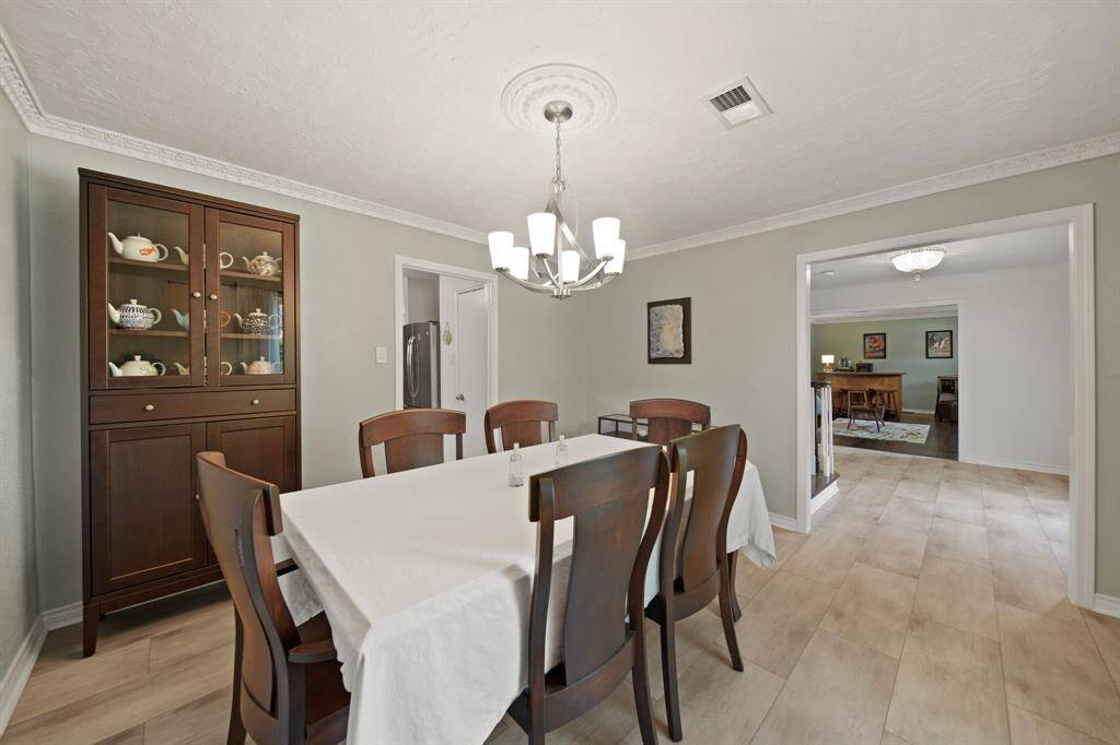 This dining room has natural light, tile floors, custom paint, and crown molding.