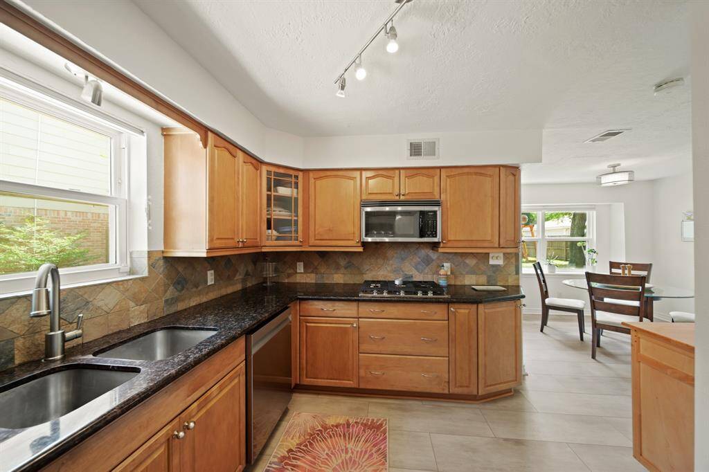 The kitchen features wood cabinets, tile floors, dark cabinets, and a large window.