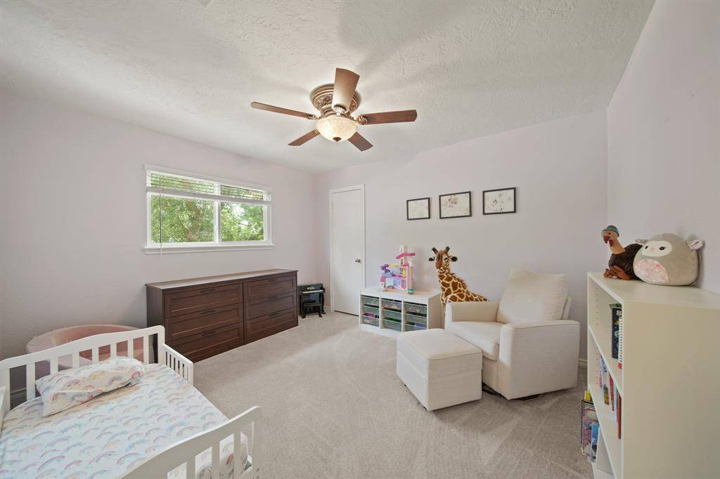 Fourth bedroom features a large window, ceiling fan, and plush carpet.