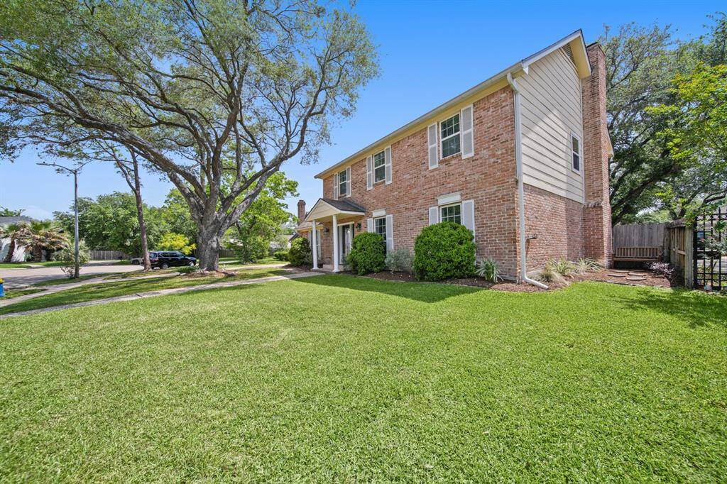 This home features brick exterior, covered front porch, lovely landscaping, and tall trees for shade.