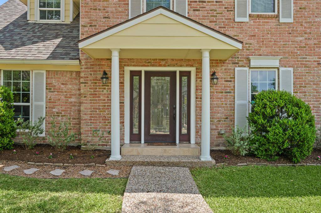Approaching the front door is the paved walkway and dark stained front door with glass details.