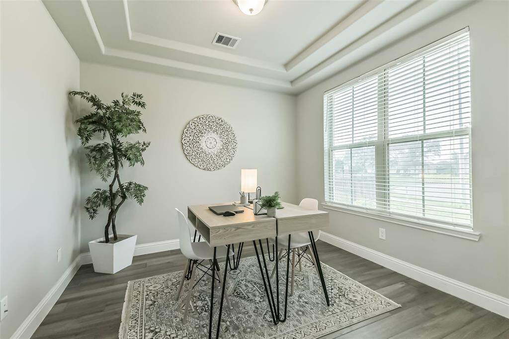 Private study has trayed ceiling and double windows that look to the trees and lake.