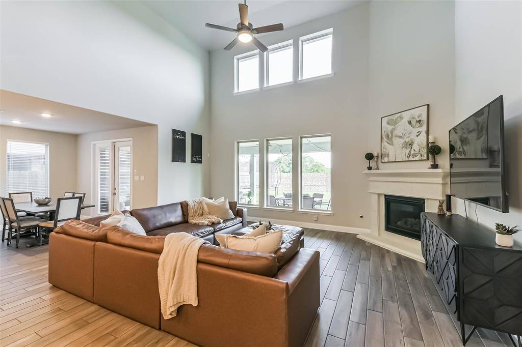 This generous family room is light and bright with a wall of windows that stretches the full 2 stories, wood look tile, ceiling fan, and gaslog corner fireplace.