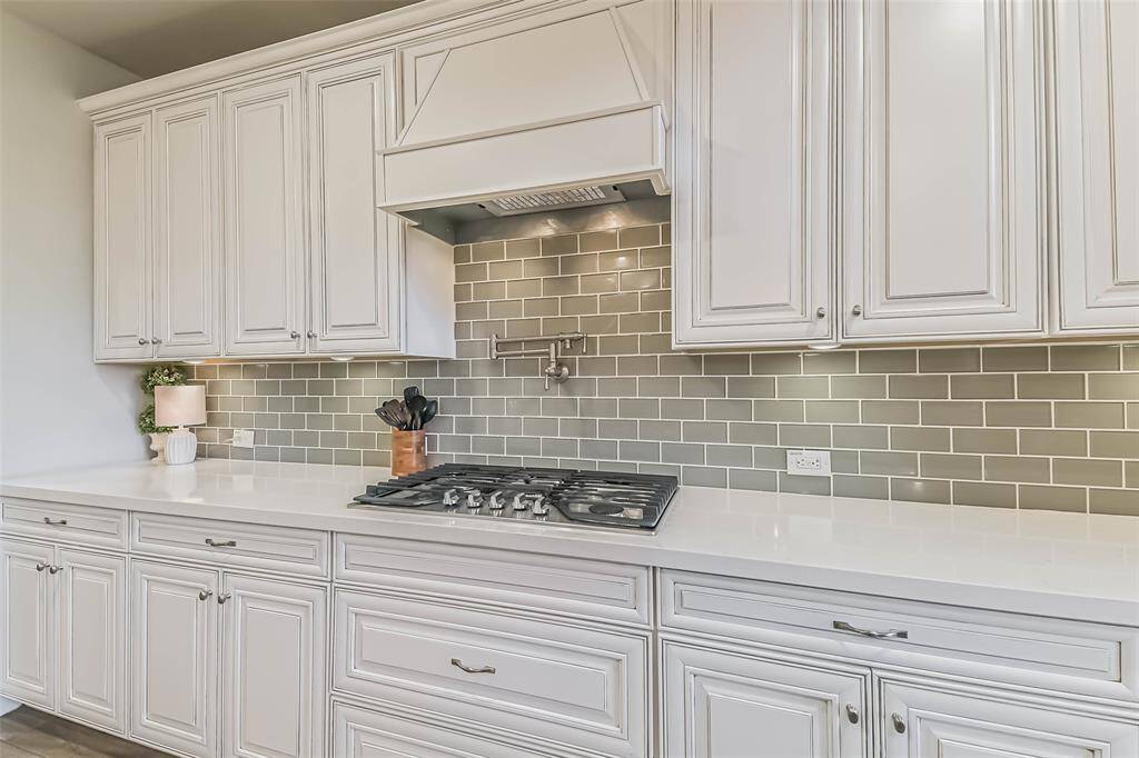 Beautiful subway tile, quartz countertops, and undercabinet lighting highlight this 5-burner gas cooktop with its upgraded vent hood and pot filler.