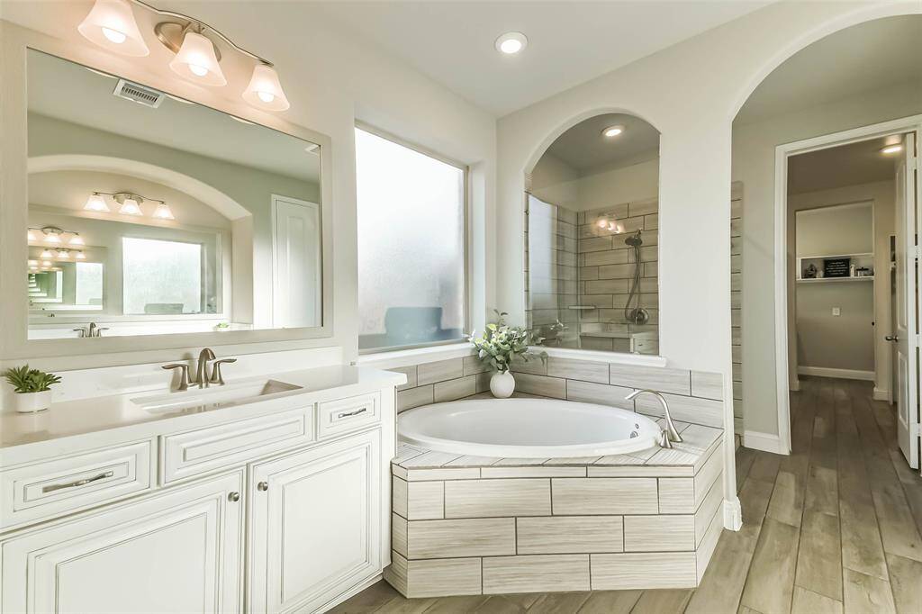 With its lovely arched details, this elegant primary bath has double sinks, a corner soaking tub, and oversized shower with upgraded fixtures. From the walk-in closet, there is an entrance straight to the laundry room.