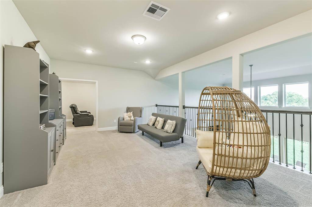 Generous game room overlooks living area below with an iron spindle railing, a view to the lake behind, and access to the media room.