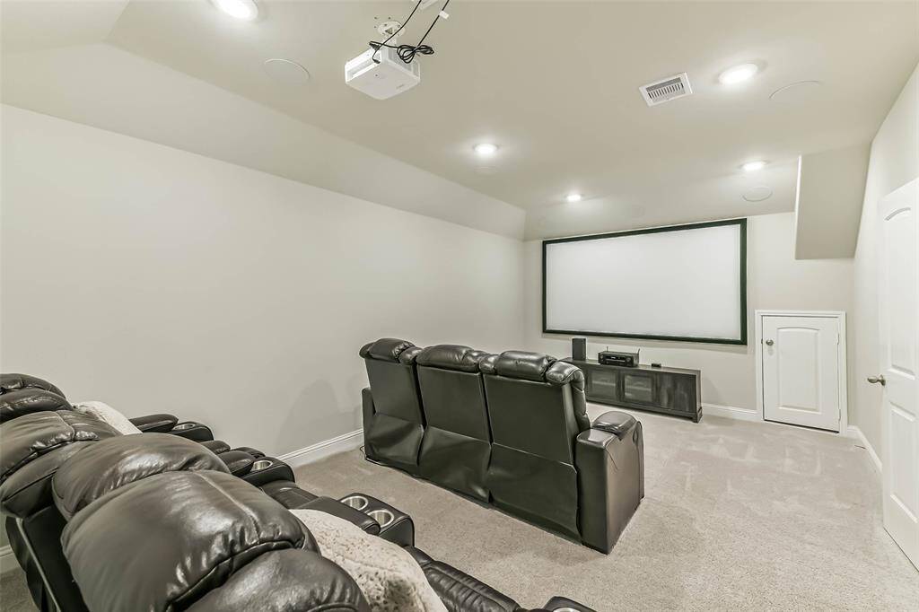 Media room has projector, oversized screen, and built-in speakers, all of which convey so the new homeowner can utilize this space immediately. Attic access leads to extra storage.