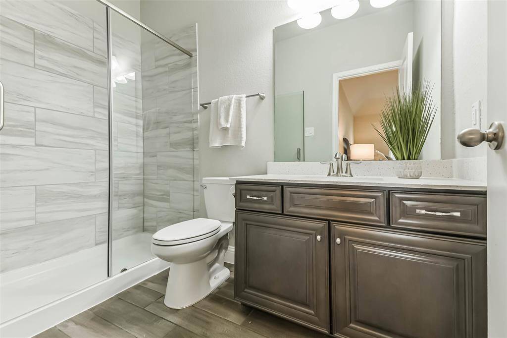 Ensuite bath for second bedroom has separate shower and wood look tile.