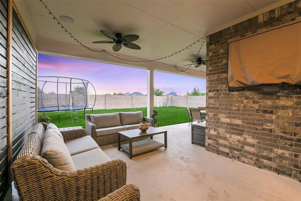 Multiple options on this extended covered back porch - watch TV, dine, or just relax and enjoy the views and sunset over the back and side brick fence.