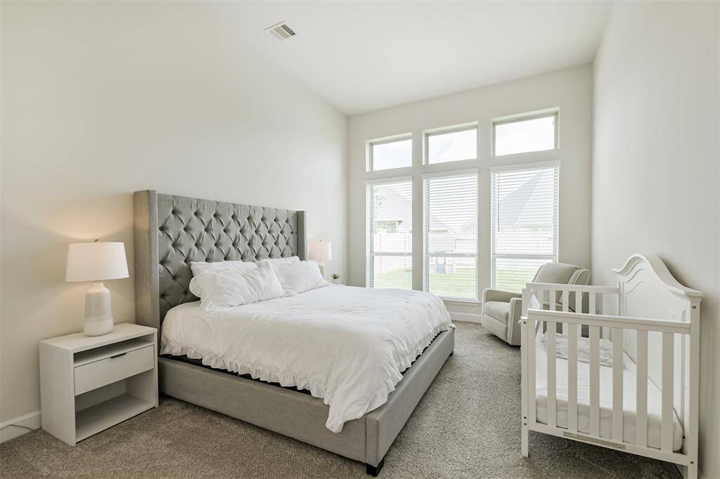 Spacious primary bedroom with room for a sitting area in front of its own wall of windows. So much natural light in this home!
