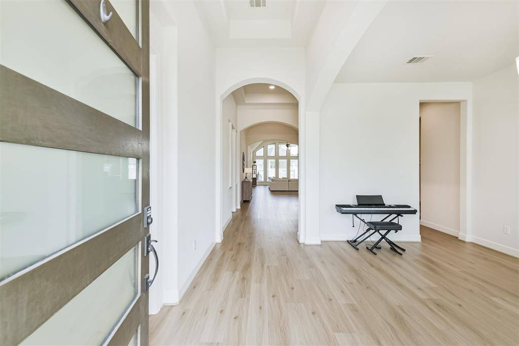 LVP flooring and trayed ceiling highlight this entry with a beautiful view of the gallery of windows in the back.