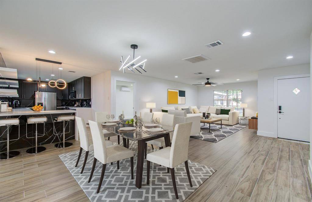 This is a spacious, open-concept living and dining area with a modern, sophisticated design. The room features an inviting layout with a sleek kitchen in the background