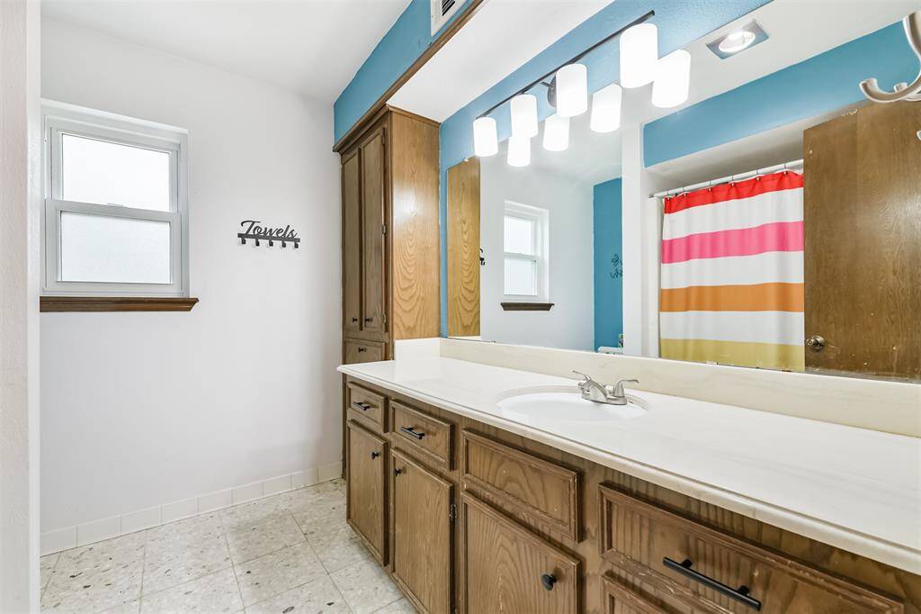 Around the corner is the second full-sized bathroom where you can see a large vanity area, plenty of storage cupboards, and tub-shower combo.