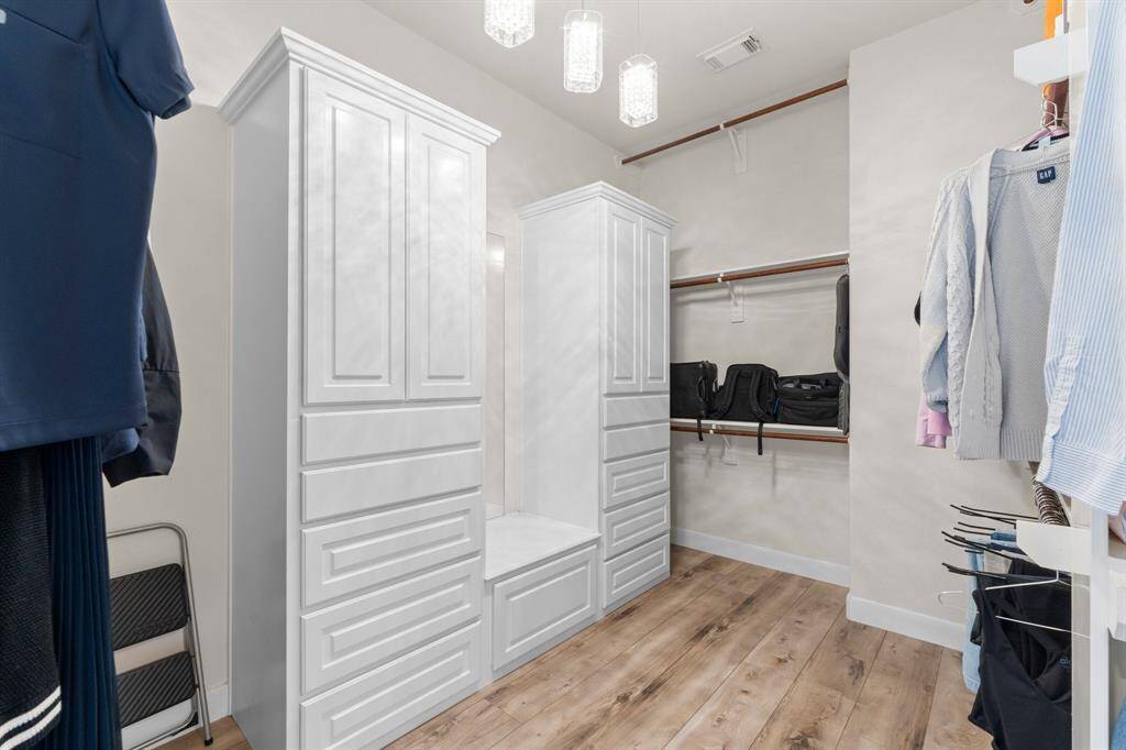 Primary closet with upgraded lighting and custom storage.