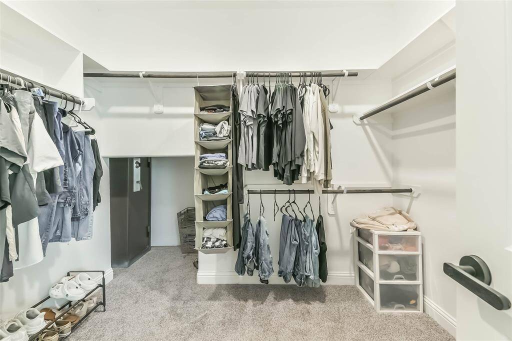 Large primary closet has added storage space under the stairs.